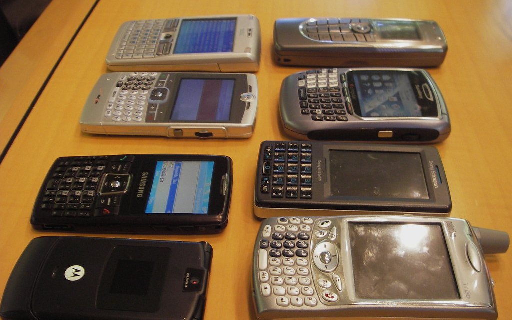 Second-hand handsets laid out on a table for sale.