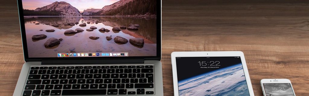 Three screens on one desk: laptop, tablet and phone.
